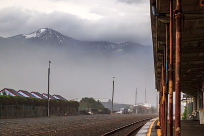 Railroad track by mountains against sky