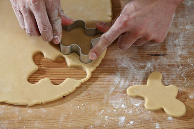 Cropped hands of chef cutting dough with pastry cutter at table