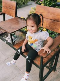 Portrait of cute boy sitting on bench in park