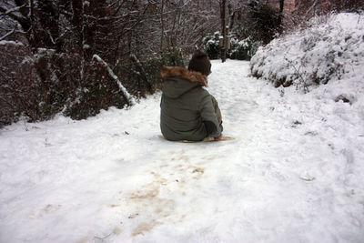 Rear view of man walking on snow covered land