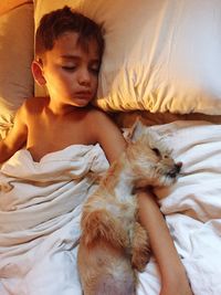 Boy sleeping with dog on bed at home