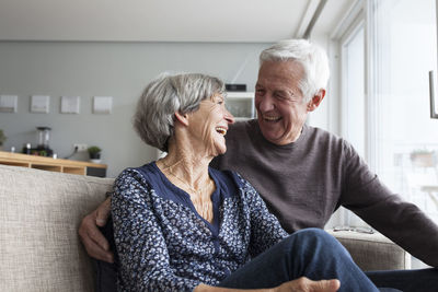 Laughing senior couple sitting together on the couch in the living room