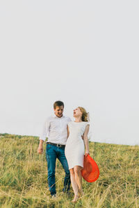 Happy friends sitting on grass against clear sky
