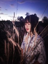 Portrait of smiling young woman standing on land against sky