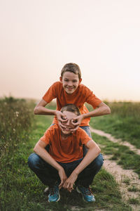 Funny twin brother boys playing outdoors on field at sunset.