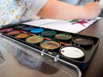 High angle view of palette on table while girl drawing