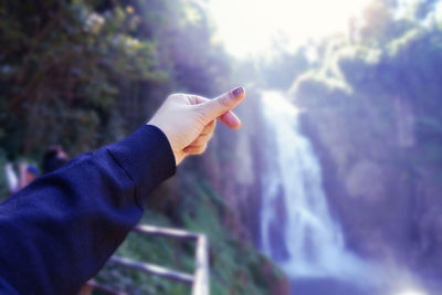 Close-up of hand holding leaf against blurred background