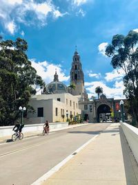 People on road amidst buildings against sky in city