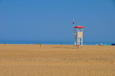 Lifeguard hut on beach against blue sky