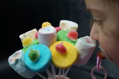 Close-up of hand holding ice cream cone against black background