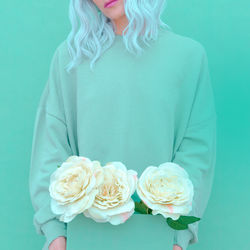 Midsection of woman with flowers against colored background