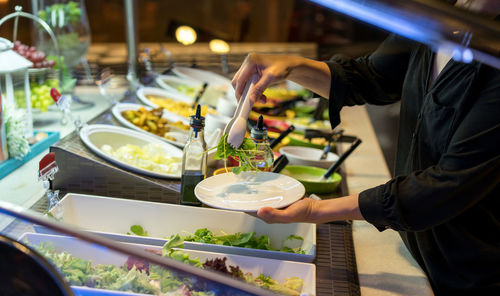 Midsection of mature woman serving food in restaurant