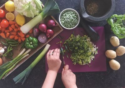 Cropped hand cutting vegetables at home