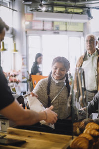 Smiling girl buying groceries at checkout in convenience store