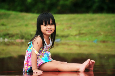 Portrait of smiling woman sitting by lake