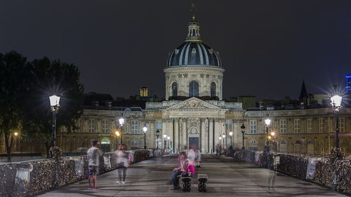 People at illuminated cathedral against sky at night
