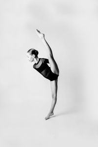Side view of woman dancing against white background