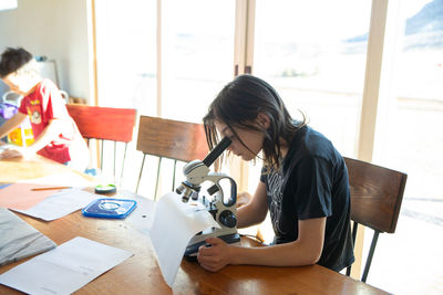 Girl examining mealworm under microscope