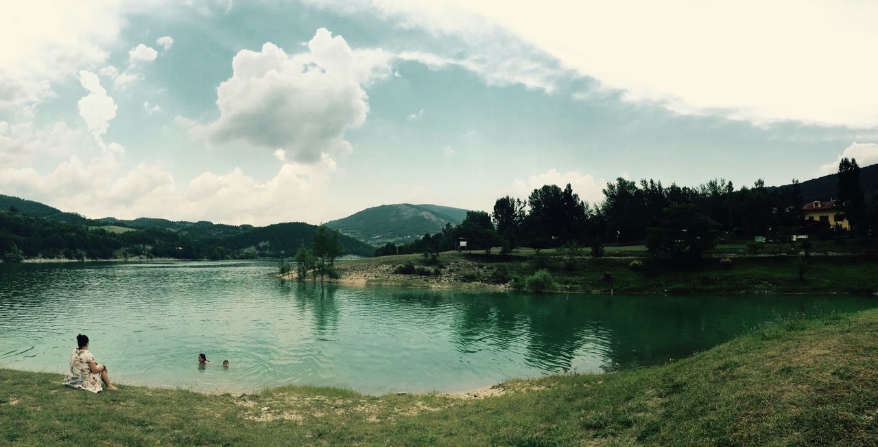 sky, water, lake, mountain, cloud - sky, leisure activity, tranquility, lifestyles, tranquil scene, tree, scenics, cloud, nature, beauty in nature, lakeshore, grass, mountain range, men