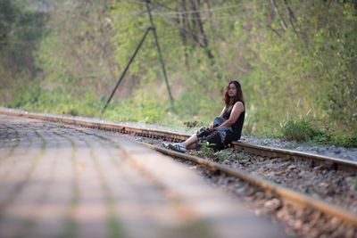Full length of woman sitting on railroad track