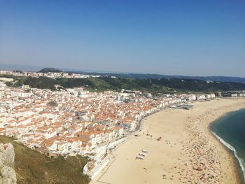 High angle view of townscape by sea against clear blue sky