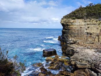 Rock formation on sea shore against sky