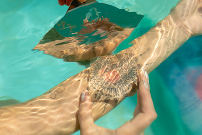 Cropped image of woman with prism on tattoo underwater