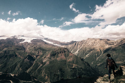 Rear view of woman standing on mountain against sky