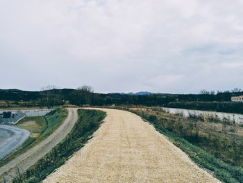 Road amidst field against sky