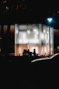 Silhouette people in illuminated building at night