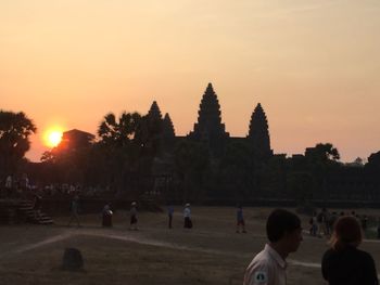 People at temple against sky during sunset