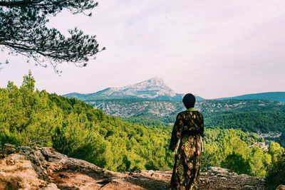 Rear view of man standing on mountain against sky