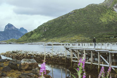 Man standing on pier over lake against sky