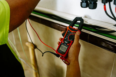 Mature engineer examining with multimeter at system in utility room