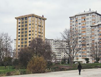 Rear view of man standing by building against sky