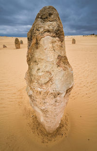 View of rocks on sand at beach against sky