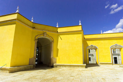 Low angle view of yellow built structure against blue sky