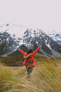 Woman standing in snow covered mountain against sky