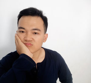 Portrait of young man standing against white background