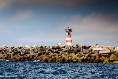 Lighthouse by sea against sky