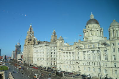 View of buildings in city against clear blue sky