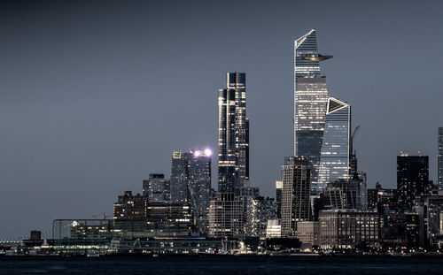 Illuminated buildings in city against sky