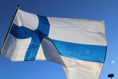 Low angle view of finnish flag against blue sky