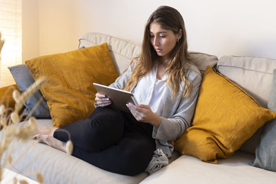 Young woman using tablet pc on sofa at home