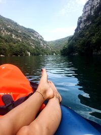 Low section of man on boat in lake against sky