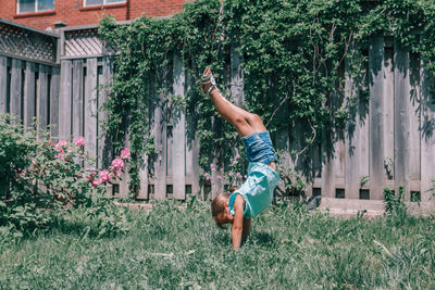 Full length of boy with arms raised against plants