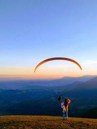 Woman looking at person paragliding against sky