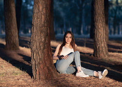 Woman sitting on tree trunk