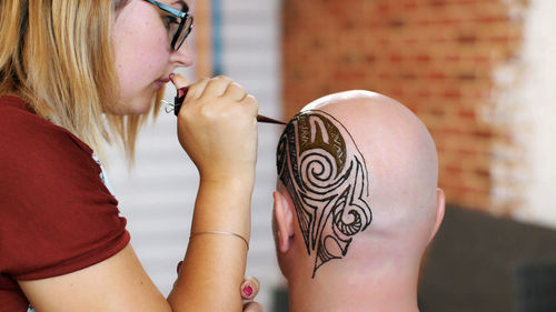 A close-up, the execution of a master, an artist mehendi,  a picture of henna on white skin scalp