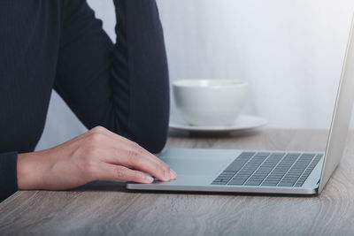 Midsection of man using laptop on table